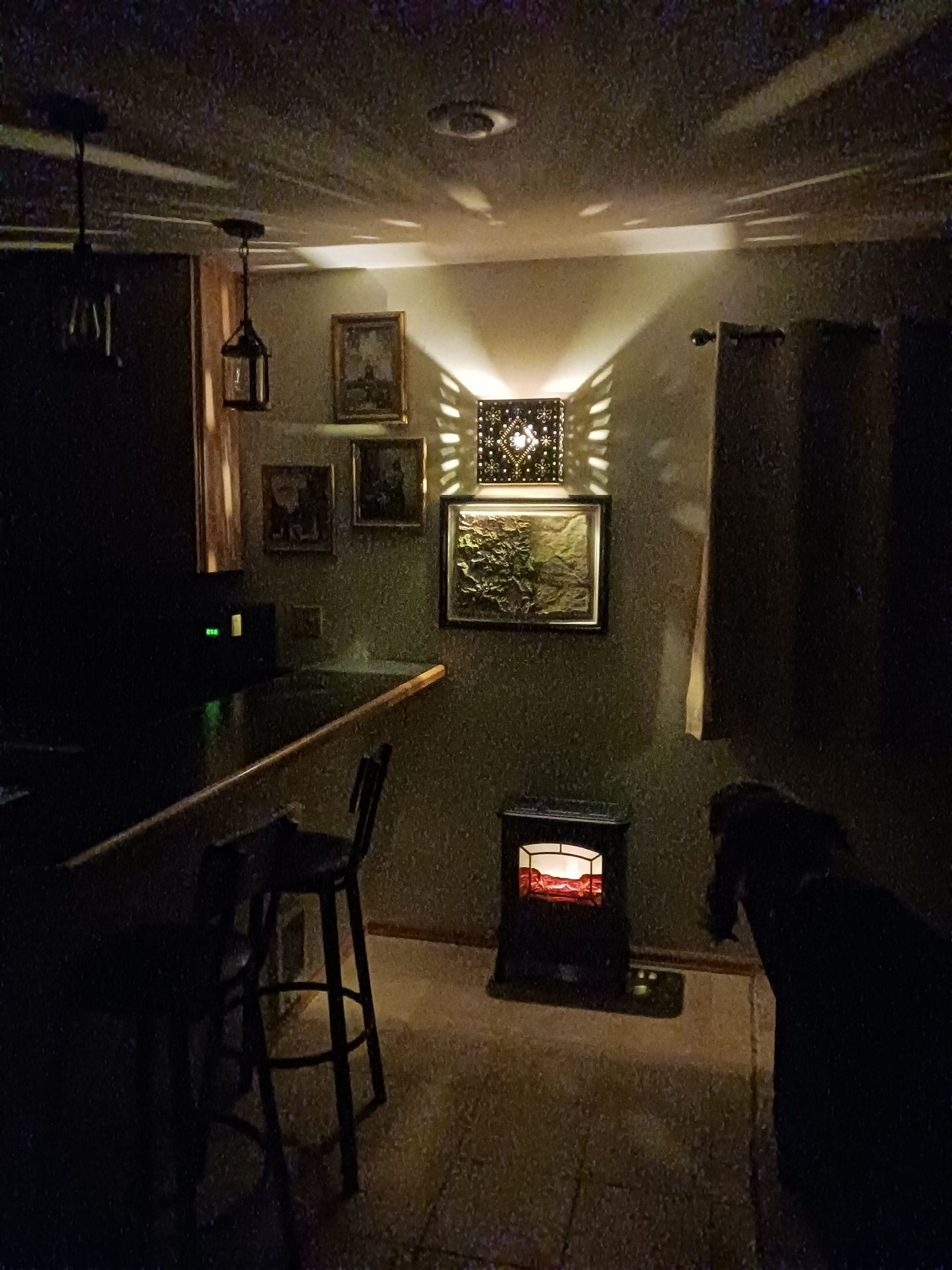 Cozy dimly lit room with a small heater and framed pictures on the wall.